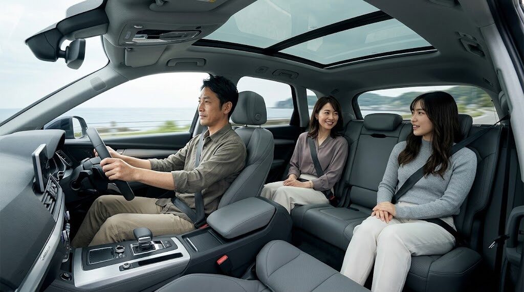 アウディQ5の広々とした車内空間。アジア人の大人3人が前席と後席にゆとりを持って座り、リラックスしてドライブを楽しんでいる様子。高い天井と横方向の広さが強調されている。